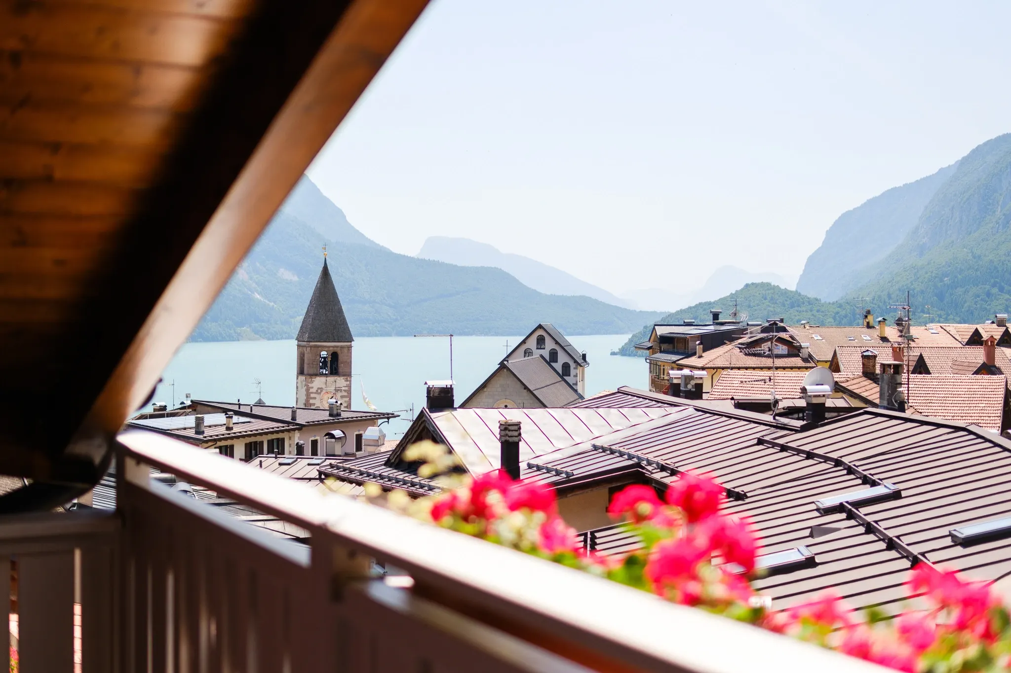 Il balcone di Cirmolo con i gerani e la vista sul lago di Molveno