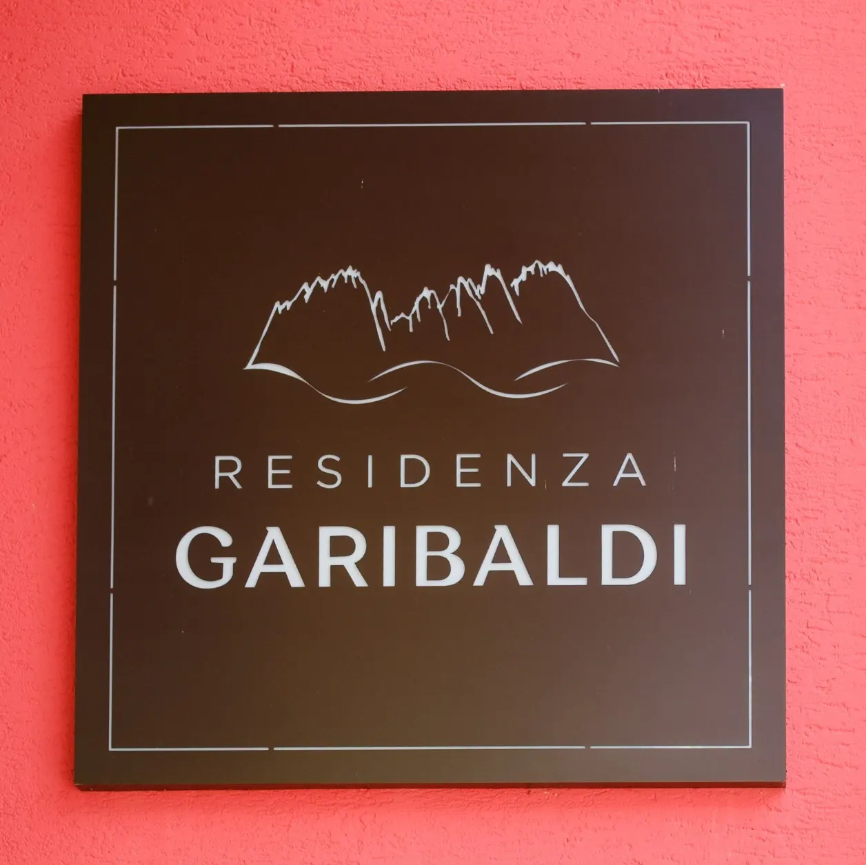 L’insegna della Residenza Garibaldi sulla parete rossa