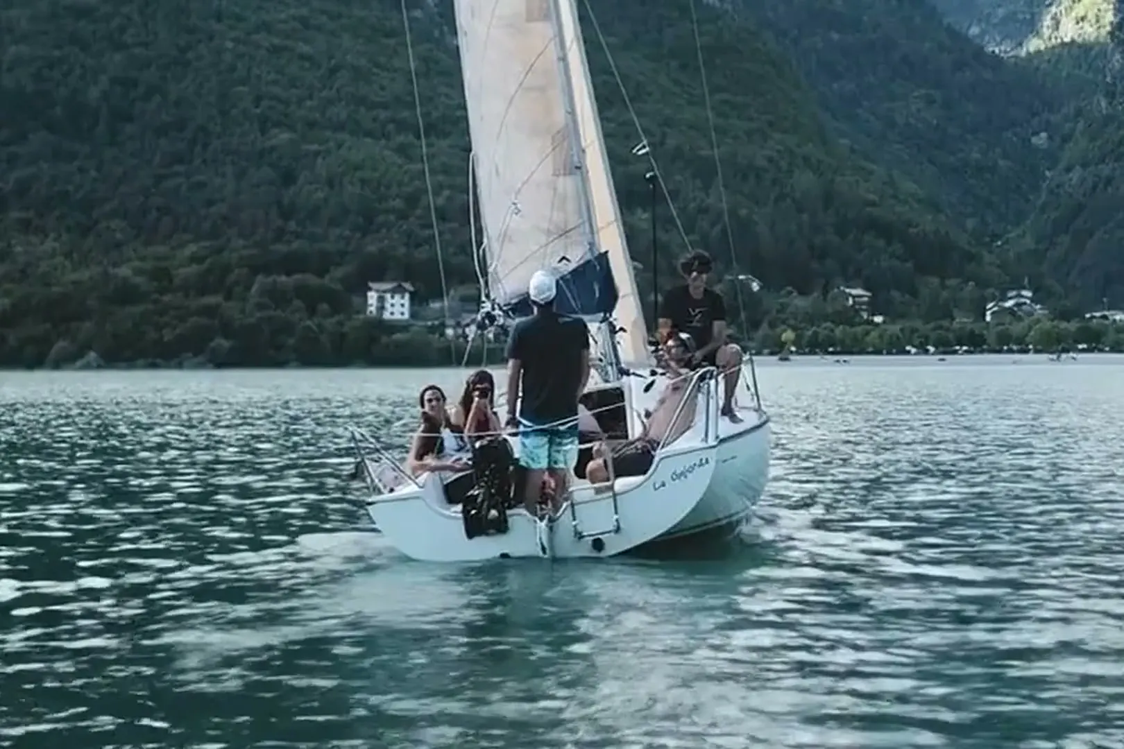 A small sailing dinghy on Lake Molveno, with the village and the Dolomites behind
